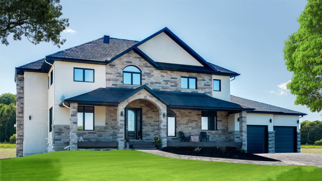 Modern two-story house with stone and stucco exterior, arched entryway, black roof, double garage, front porch with seats, and manicured green lawn, set against a clear sky and trees—a stunning example that highlights the difference between net zero & net zero ready homes for those considering energy-efficient living.