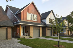 A row of modern suburban houses with garages, front porches, and well-kept lawns lines a quiet street, exemplifying the growing trend of net zero homes in thoughtfully designed communities.