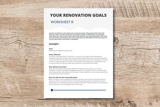 A renovation worksheet titled Your Renovation Goals lies on a wooden surface. The worksheet includes example text about setting renovation goals, areas affected, and the addition of new features.