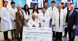 A group of people smiles while holding a large ceremonial check for $20 million to The Ottawa Hospital Foundation, with The Kris Singhal Family written on it and the date November 29, 2023.